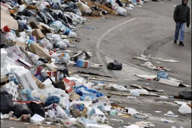 AFP PHOTO / A man walks near heaps of uncollected garbage in a suburb of Naples, southern Italy, 05 January 2008.