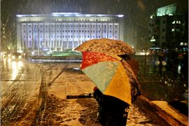 AFP / Syrian pedestrians stand under their umbrellas during a snow storm near the Central Bank in Damascus 22 January 2008. A wave of cold weather and snow storms is hitting the