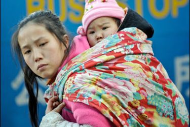 AFP PHOTO/A Chinese women carry a child on her back at a railway station in Beijing, 26 January 2008.