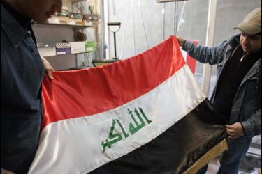AFP PHOTO/An Iraqi tailor (R) inspect the new Iraqi national flag after he sewed it at his workshop in central Baghdad on February 5, 2008.