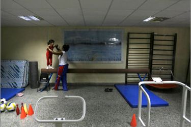 REUTERS/An autistic child walks next to a teacher during a therapy session at the Dora Alonso Autismo Center in Havana February