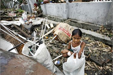 REUTERS/ A girl sits amidst debris outside of her home southwest of Yangon May 7, 2008. Aid trickled into Myanmar on Wednesday for an estimated one million victims of Cyclone