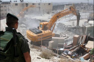 f/An Israeli border policeman looks at an army bulldozer destroying a Palestinian house in the east Jerusalem neighborhood of Atur on May 21, 2008