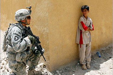 REUTERS /A boy looks at a U.S. soldier on guard during the opening of a new community centre in a village in Sayafiyah southeast of Baghdad May 20, 2008. REUTERS/Erik de Castro (IRAQ)