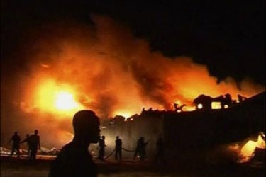r : An image taken from video footage shows rescue workers fighting the flames of a Sudan Airways plane after it burst into flames upon landing at Khartoum airport June 10, 2008. The