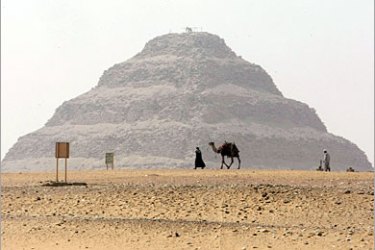 AFP - A man walks with his camel on a foggy day past the Step Pyramid of Sakkara, south of Cairo, on June 5, 2008. The structure dates back the Third Dynasty 2667 to 2648 BC,