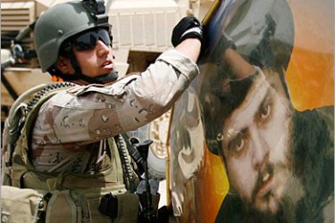 REUTERS /An Iraqi soldier holds a poster of anti-U.S. cleric Moqtada al-Sadr seized during a raid in Amara, 300 km (185 miles) southeast of Baghdad, June 20, 2008. Supporters of anti-