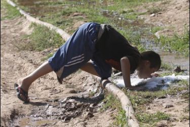 REUTERS/A boy drinks water from a broken pipe in the village of Sangtuda, about 150 km (94 miles) south of Dushanbe, May 28, 2008. Picture taken May 28, 2008.