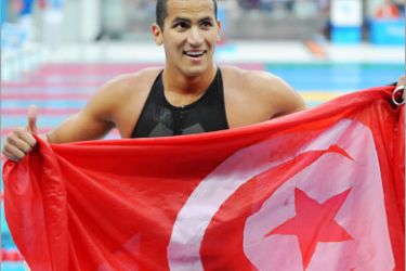 AFP / Oussama Mellouli of Tunisia holds his county's flag after the men's 1500m freestyle swimming final at the National Aquatics Center during the 2008 Beijing Olympic Games in