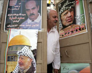 فلسطيني يحمل صور الرئيس الراحل ياسر عرفات وأقدم المعتقلين سعيد العتبة (الفرنسية)