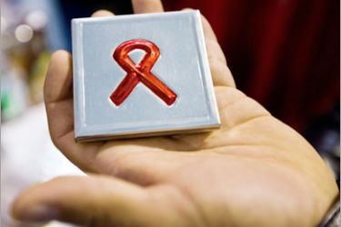 AFP / A man holds a pillbox with the AIDS ribbon on sale at the Global Village in Mexico City on August 3, 2008 during an exhibition in the framework of the XVII International AIDS/HIV