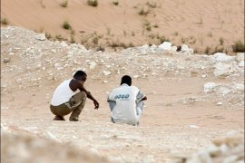 r : Two Nigerian men sit in a border area north of Sinai near Israel as they wait to be smuggled into Israel August 5, 2008. An increasing number of African migrants try to cross the