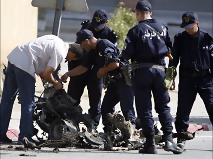 r_Police officers inspect pieces of wreckage from a car bomb at the site of a car bomb attack in Bouira, 150 km (90 miles) east of Algiers, August 20, 2008.