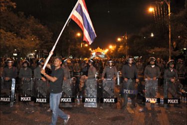 f_A Thai anti-government walks wit ha flag in front of Thai Riot police blocking a street during a demonstration on September 2, 2008 near the Government House, in Bangkok
