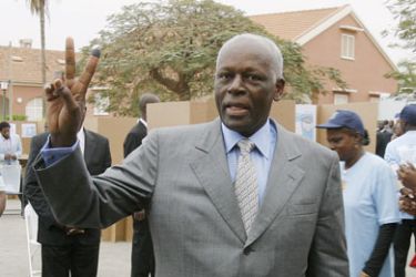 Angolan President Jose Eduardo Dos Santos gives the victory sign showing his ink marked finger as prove of his ballot cast on September 5, 2008 at the polling station behind