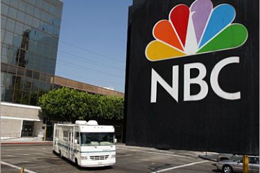 /AFP / The NBC peacock logo hangs on the NBC studios building as a mobile home is parked nearby on October 20, 2008 in Burbank, California. NBC Universal plans another round of major cuts totaling $500 million from the next yearly budget in spite of recent