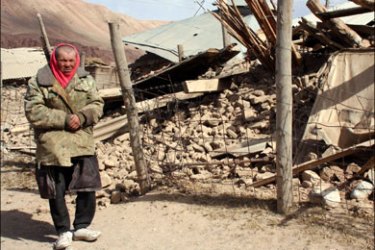 afp : A Kyrgyz man stands near a destroyed house at the site of a major earthquake in Nura on October 6, 2008. Rescuers raced to reach a remote village in Kyrgyzstan on Monday