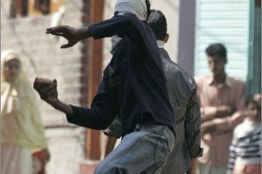 REUTERS/A masked Kashmiri protester throws a brick at Indian policemen during a protest against Indian Prime Minister Manmohan Singh's visit, in Srinagar