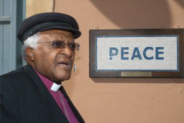 South African cleric and anti-apartheid campaigner Desmond Tutu walks past a street mosaic which reads 'Peace' on the green line that separates the Greek Cypriot side from the Turkish military-controlled areas in the heart of Nicosia on October 9, 2008.