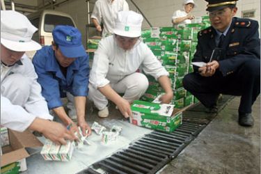 AFP Chinese enforcement officer watches as workers destroy some 2,784 boxes of contaminated Mengniu milk that were recalled in Wuhan, central China's Hubei province on November 5, 2008. China is in the midst of a food scandal after an industrial chemical called melamine was discovered in milk made by 22 Chinese companies and then in eggs, while the tainted
