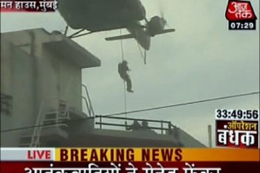afp : This television grab from Indian channel AAJTAK TV shows military personnel as they abseil from a helicopter onto a roof of a building in Mumbai early November 28,
