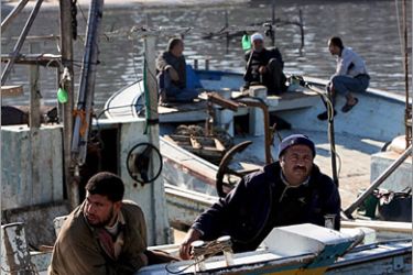 epa01565292 Palestinian fishermen sit on the rim of their vessel as they wait to recieve a Libyan boat carrying food and medical supplies sail from Sabratha port to Gaza Strip