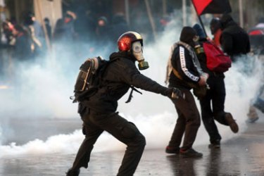 AFP/ Protesters throws stones at riot police during a demonstration outside of a regional government ministry office in the northern Greek city of Thessaloniki on December 10, 2008.