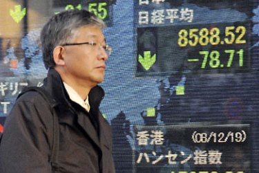 ف- A pedestrian walks in front of a share prices board in Tokyo on December 19, 2008. Japan's share prices fell 78.71 points to close at 8,588.52 points at the Tokyo Stock Exchange on persistent economic worries,