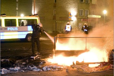 epa01581242 Swedish police extinguish burning barricades on the main road in the immigrant-dominated suburb of Rosengard in Malmo in southern Sweden, 19 December