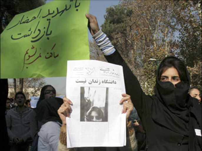 r : A student holds a placard reading: "Threats of summons and arrest will not silence us", during a student day demonstration inside Tehran University December 7, 2008.