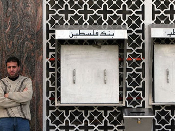 afp : A Palestinian man stands outside a bank with locked ATMs in Gaza city on December 6, 2008. Banks in the Gaza Strip closed their branches this week due to lack of liquidity