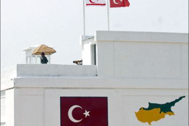 afp : (FILES) A picture taken on May 10, 2003 shows Turkish soldiers standing above a painting of their national flag and a map of the divided island of Cyprus as they monitor the