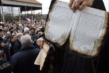 r_A Muslim man displays burnt holy books to the crowd at a demonstration outside a mosque the day after an arson attack in Saint-Priest, near Lyon, southeastern