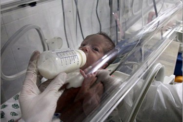 AFP - A Palestinian medic feeds a baby at an incubator in Gaza City’s southern al-Quds hospital, after a section of the medical facility was hit by Israeli fire, early on January 15,