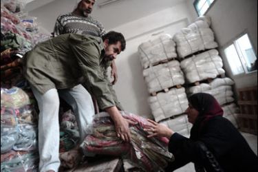 f/Palestinian workers with the UNRWA (United Nations Relief and Works Agency) distribute blankets to homeless people at the organization’s warehouse in Gaza City on January 29, 2009.