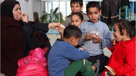 اسرة فلسطينية تتناول الخبز في احدى مدارس الوكالة التي لجأت لها - الجزيرة نت