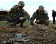 جنود إسرائيليون يتفقدون مكان سقوط الصاروخ (رويترز)