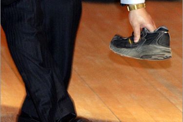 AFP - A security guard picks up a shoe that was thrown towards Chinese Premier Wen Jiabao at the University of Cambridge, some 95 kms north of London, on February 2, 2009 at the