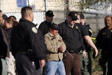 afp : PHOENIX - FEBRUARY 11: A worker is arrested as Maricopa County Sheriffs conduct an immigration raid at HMI Contracting February 11, 2009 in Phoenix, Arizona. Several