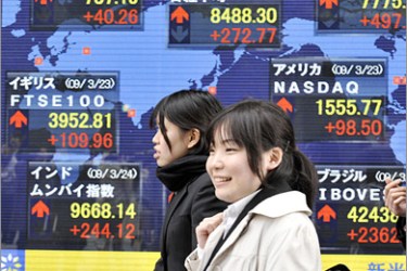 AFP - Pedestrians walk past a share prices board in Tokyo on March 24, 2009. Japanese share prices rose 272.77 points to close at 8,488.30 on the Tokyo Stock Exchange as