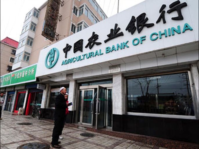 afp : Muslims from China's Hui minority walk past a branch of Agricultural Bank of China in Xining on March 11, 2009 in northwest China's Qinghai province. Agricultural Bank of