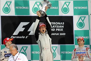 AFP - British formula one driver Jenson Button (C) of Brawn-Mercedes shouts as he lifts the trophy after receiving it from Malaysian Prime Minister Najib Razak (2nd L), as Germany's Nick Heidfeld (L) of BMW Sauber and compatriot Timo Glock of Toyota look on at the end of the Malaysian Grand Prix in