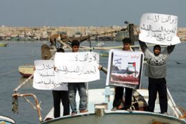 Palestinian youths hold slogans against the Israeli naval blockade on the Gaza Strip at the port in Gaza City on April 13, 2009. The Israeli navy blew up a fishing boat filled