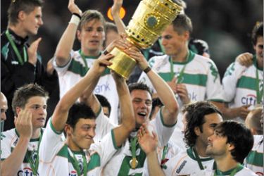 Werder Bremen's midfielder Mesut Oezil (L) holds the trophy and celebrates with teammates and Werder Bremen's Brazilian midfielder Diego (R) after the men's DFB German Cup final football match Werder Bremen vs Bayer Leverkusen on May 30, 2009 at the Olympic stadium in Berlin. Werder Bremen won 1-0 and is German Cup winner.