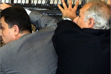 Relatives of Egyptian tycoon Hisham Talaat Mustafa hide him from the media as he sits in the dock waiting for his sentence at a Cairo court on May 21, 2009.