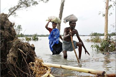 REUTERS / Flood-affected villagers make their way through the cyclone-hit area of Shabakhali in the Sundarbans delta, about 100 km (62 miles) southeast from the eastern Indian city of Kolkata May 27, 2009. Nearly 200 people have been killed by a cyclone that ripped through Bangladesh and eastern India, while millions remained marooned by floodwater or forced to