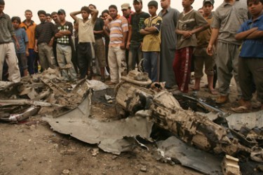 Iraqis gather around the remains of a vehicle used as a car bomb that exploded at a wholesale produce market near the mixed neighbourhood of Dura in a southern district
