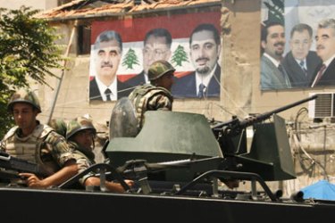 Lebanese soldiers on a armoured personnel carrier patrol a street in Sidon, southern lebanon, May 27, 2009. In the background, electoral campaign posters of assassinated