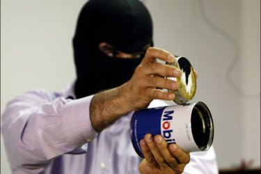 afp ; A masked Lebanese secret service officer shows to the media at the Lebanese security services headquarters in Beirut on May 11, 2009 a can of motor oil used to