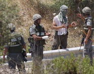 مستوطن يرتدي لثاما أثناء محاولته حرق مزارع الفلسطينيين (الجزيرة نت)
